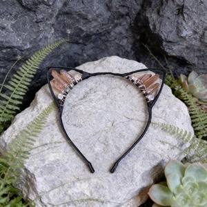 Detail of handmade cat ear headband with champagne crystals on a natural rock background