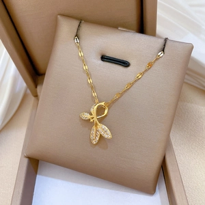 Detailed view of a gold leaf pendant with inlaid zircons resting on a brown jewelry box cushion