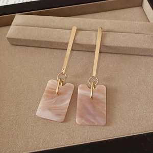 Detail of elegant gold bar earrings with marble pink acetate rectangular pendants
