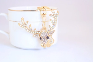 Macro view of gold crystal reindeer keychain with lobster clasp on ceramic cup