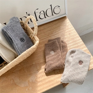 Detail of thick cable knit winter socks with delicate rose flower embroidery on side