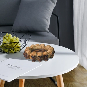Gothic skull head round ashtray made of brown resin placed on a modern white coffee table