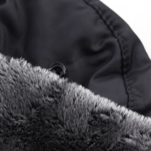 Close-up of windproof winter hat featuring grey faux fur lining and black metal snap button