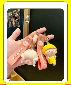 Close-up of cute pink pig keychains featuring scooters and PVC hand straps