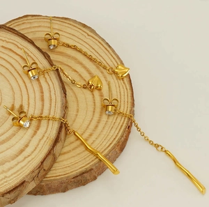 Detail of gold tassel earrings with heart pendants and crystals on a wooden base
