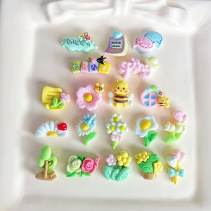 Colorful floral and bee resin charms for DIY nail art and jewelry on white plate