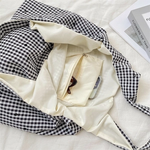Interior detail of gingham tote bag featuring a zip pocket with phone and sunglasses