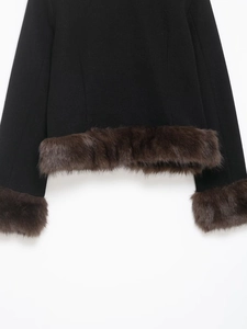 Detail of wool fabric with fluffy brown faux fur trim on cuffs and hem of a black jacket