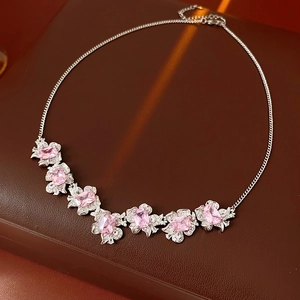 Macro shot of silver flower necklace with seven pink gems on brown leather surface