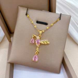 Close-up of golden swallow pendant with pink gemstones and white zircons in a jewelry box