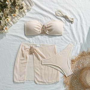 Detail of waffle textured beige bikini top and sarong with golden metal hardware