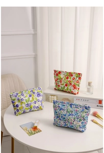 Juego de tres bonitas bolsas de maquillaje con motivos florales y de bayas en mesa