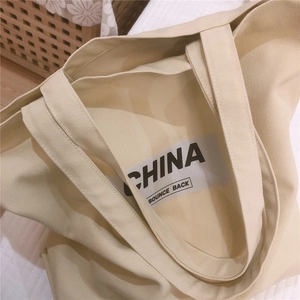 Gros plan sur le sac cabas en toile beige avec impression CHINA BOUNCE BACK en noir