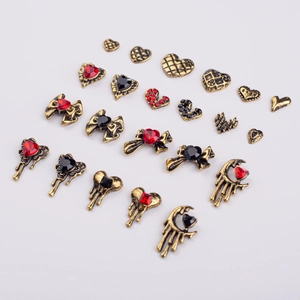 Detailed view of vintage gold nail art charms with heart and bow designs and red rhinestones