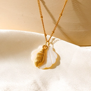 Détail des pendentifs étoile de mer et coquillage sur chaîne dorée et tissu en soie