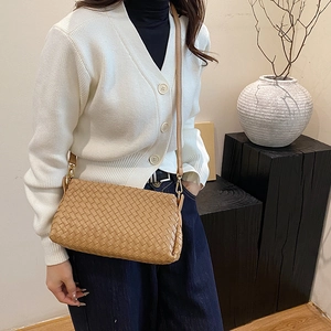 Elegante borsa a tracolla intrecciata color kaki indossata da una modella in casa