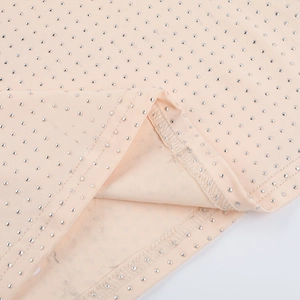 Détail du tissu en maille rose abricot avec embellissements de strass argentés scintillants