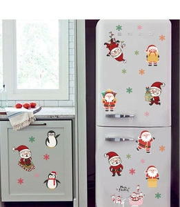 Detailed view of cartoon Santa, penguin and snowflake stickers on a white fridge door