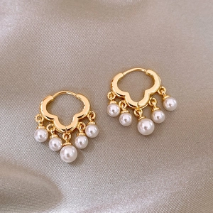 Detail of gold pearl earrings with fan-shaped drop pendants on champagne silk fabric