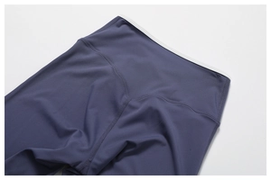 Macro detail of slate blue high-waisted yoga pants with white contrast piping and V-seams