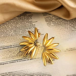Detail of 18K gold petal earrings on vintage book with champagne silk background