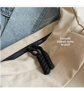 Detail of high-quality smooth zipper and durable nylon fabric on beige crossbody bag