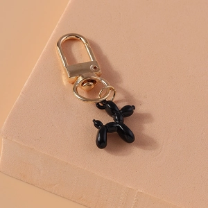 Macro detail of glossy black resin balloon dog keychain with shiny golden metal ring