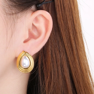 Close-up of elegant gold waterdrop earrings with inlaid white pearls on model