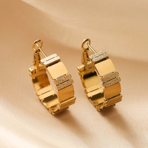 Luxurious geometric gold titanium earrings with matte and polished texture on silk background