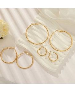 Three pairs of gold stainless steel hoop earrings in various sizes on a white display