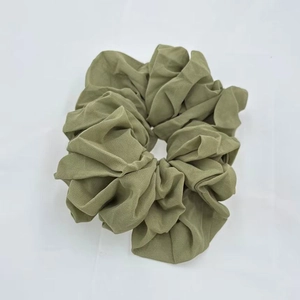 Close-up of a green chiffon scrunchie with high elasticity and elegant pleated texture