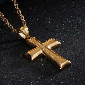 Close-up of gold-plated stainless steel cross pendant with twisted rope chain on dark background
