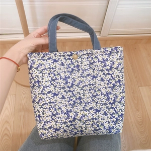 Detail of floral canvas lunch bag featuring blue floral pattern and golden metal snap button