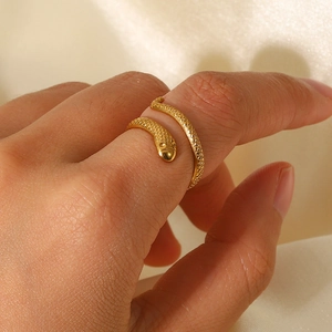 Macro shot of gold snake-shaped adjustable ring with detailed scale texture on finger
