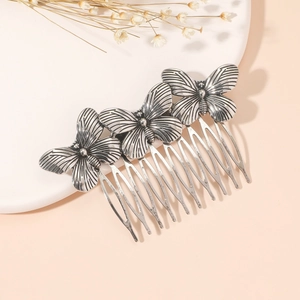 Detailed view of three vintage silver butterfly ornaments on a metal hair comb