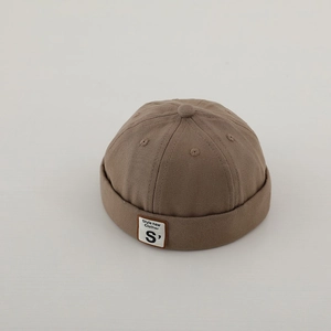 Dettaglio del cappello docker marrone in tela con etichetta quadrata bianca