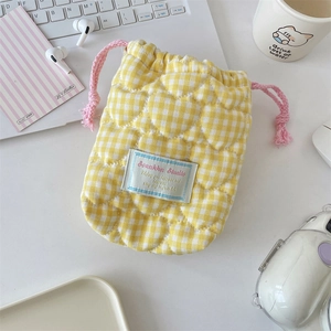 Detailed view of yellow checkered quilted camera bag with heart stitching and pink drawstring