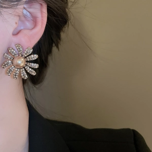 Close-up of elegant flower stud earrings with sparkling crystals and champagne pearls