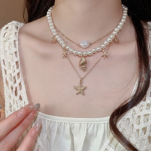 Close-up of triple-layered necklace with starfish, seashell and baroque pearl charms