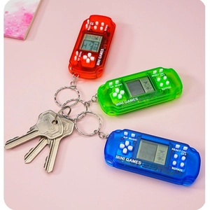 Three mini handheld Tetris game console keychains in red, green, and blue on pink surface