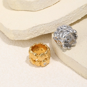 Macro detail of gold and silver textured lava rings with inlaid zircons on stone