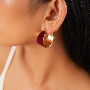 Close-up of elegant burgundy velvet and gold semi-circle earrings worn by a model