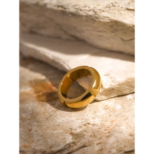 Minimalist 18k gold plated stainless steel ring on a textured stone background