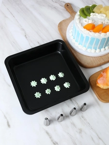 Black non-stick baking tray with stainless steel piping tips and cream decorations