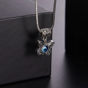 Detail view of silver butterfly necklace with blue evil eye pendant on black jewelry box