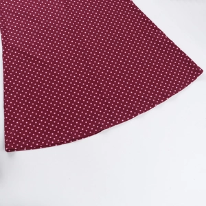 Dettaglio dell'orlo curvo e motivo a pois rosa su tessuto rosso bordeaux