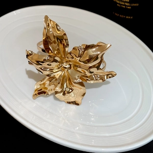 Detailed close-up of a large gold blooming flower bracelet with metallic textures