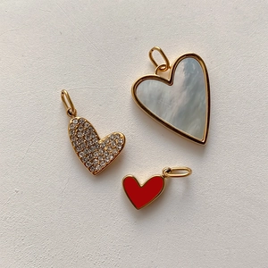 Detailed view of heart-shaped pendants with white shell, gold plating and red enamel finish