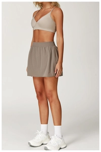 Dettaglio del reggiseno sportivo beige e gonna da tennis talpa con ampia fascia elastica