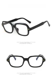 Detail of square black eyewear frame with transparent lenses and gold rivet accents